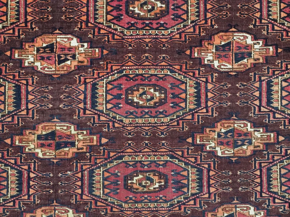 An antique Saryk Turkmen chuval face featuring nine octagonal Salor guls in deep crimson, brown, and white with geometric borders. View X