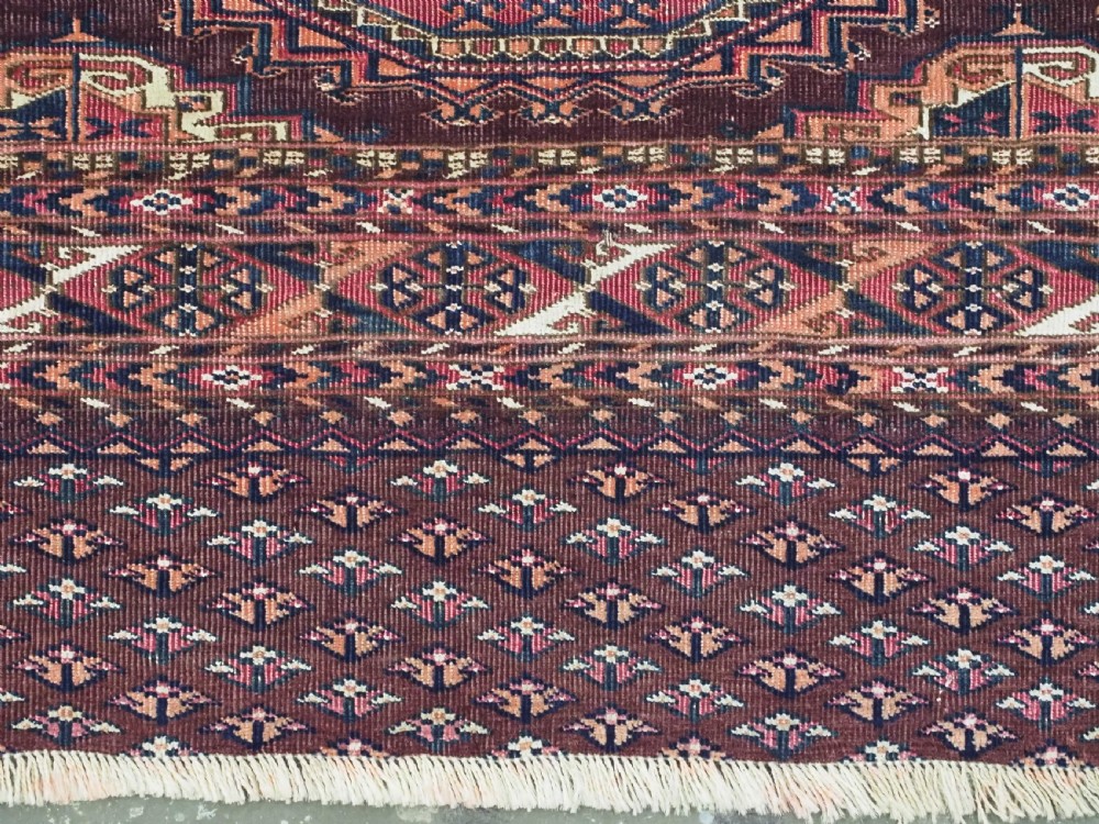 An antique Saryk Turkmen chuval face featuring nine octagonal Salor guls in deep crimson, brown, and white with geometric borders. View XI