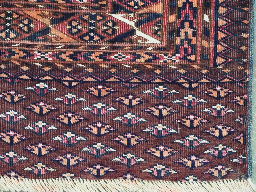 An antique Saryk Turkmen chuval face featuring nine octagonal Salor guls in deep crimson, brown, and white with geometric borders. View XII