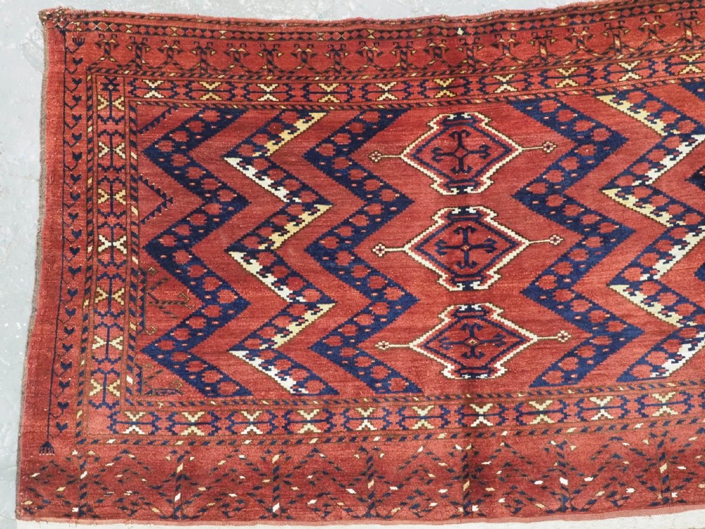 A rectangular hand-knotted wool chuval face featuring red and navy blue geometric chevron ikat patterns within decorative borders. View II