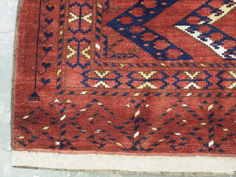 A rectangular hand-knotted wool chuval face featuring red and navy blue geometric chevron ikat patterns within decorative borders. View VI