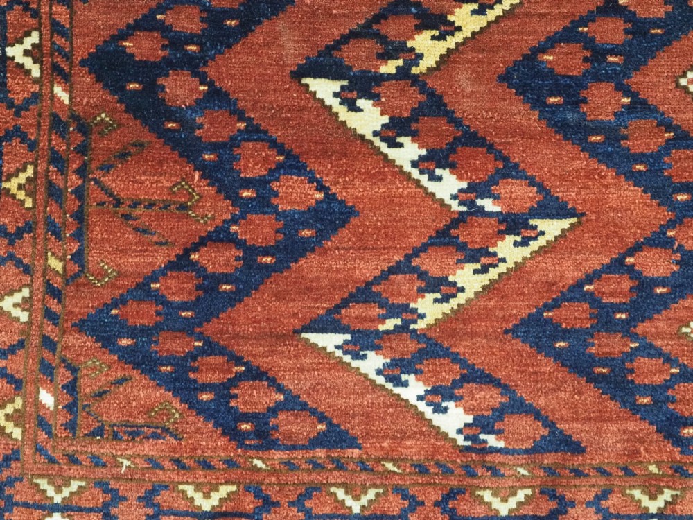 A rectangular hand-knotted wool chuval face featuring red and navy blue geometric chevron ikat patterns within decorative borders. View VII