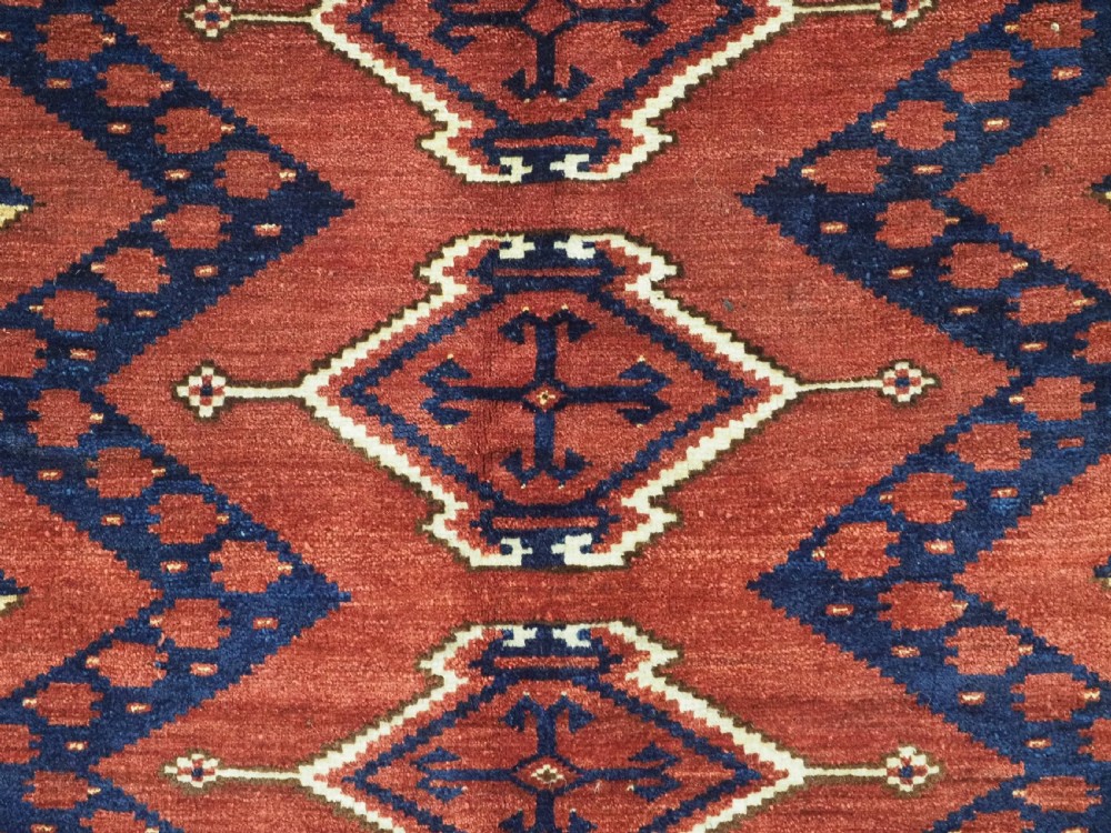 A rectangular hand-knotted wool chuval face featuring red and navy blue geometric chevron ikat patterns within decorative borders. View VIII
