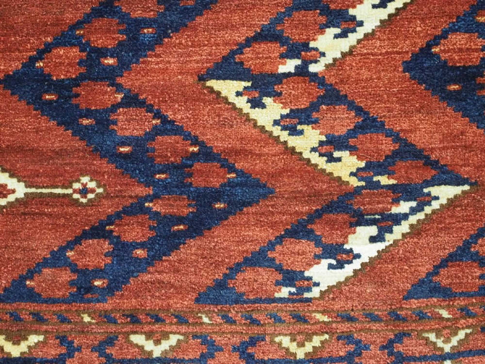A rectangular hand-knotted wool chuval face featuring red and navy blue geometric chevron ikat patterns within decorative borders. View XI