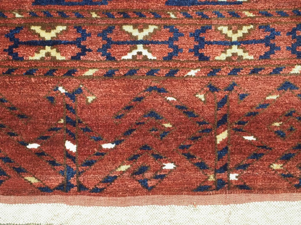 A rectangular hand-knotted wool chuval face featuring red and navy blue geometric chevron ikat patterns within decorative borders. View XII
