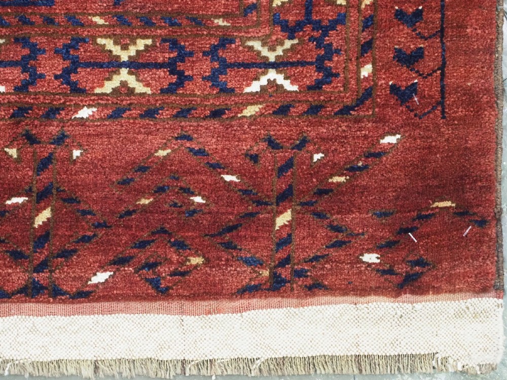 A rectangular hand-knotted wool chuval face featuring red and navy blue geometric chevron ikat patterns within decorative borders. View XIII