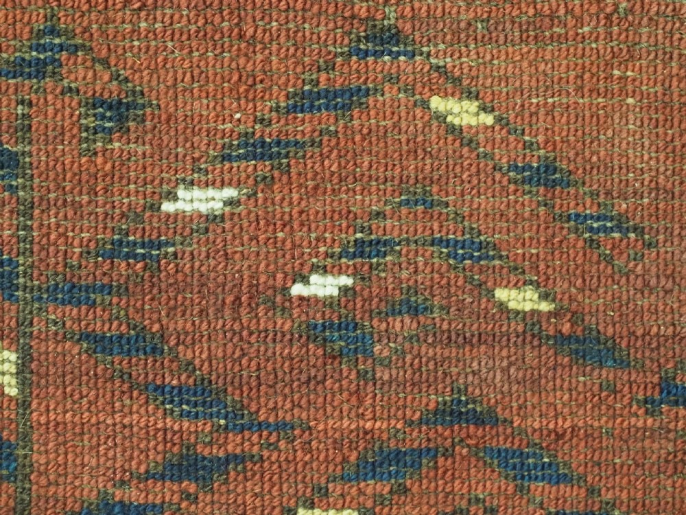 A rectangular hand-knotted wool chuval face featuring red and navy blue geometric chevron ikat patterns within decorative borders. View XIV