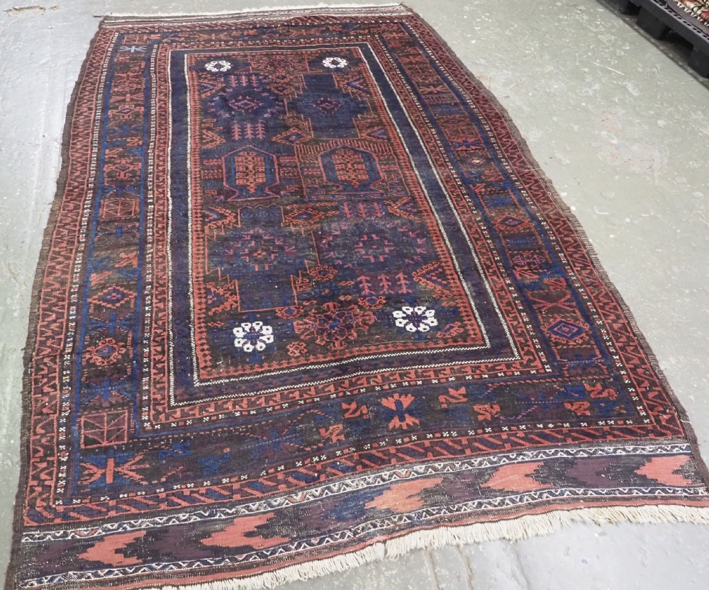 A rectangular antique hand-knotted wool carpet featuring deep indigo blue and madder red geometric motifs with geometric borders and white star details. View II