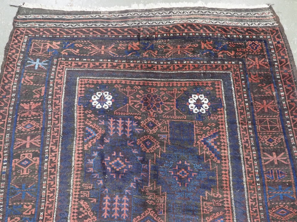 A rectangular antique hand-knotted wool carpet featuring deep indigo blue and madder red geometric motifs with geometric borders and white star details. View III