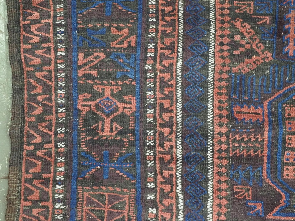 A rectangular antique hand-knotted wool carpet featuring deep indigo blue and madder red geometric motifs with geometric borders and white star details. View V