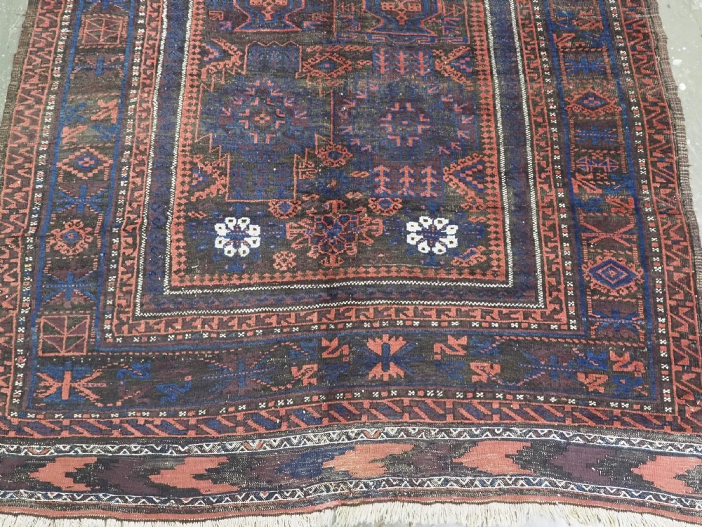 A rectangular antique hand-knotted wool carpet featuring deep indigo blue and madder red geometric motifs with geometric borders and white star details. View VI