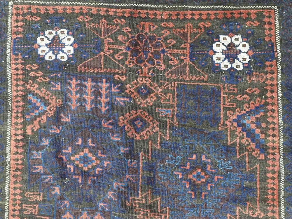 A rectangular antique hand-knotted wool carpet featuring deep indigo blue and madder red geometric motifs with geometric borders and white star details. View VIII