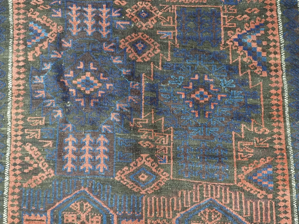 A rectangular antique hand-knotted wool carpet featuring deep indigo blue and madder red geometric motifs with geometric borders and white star details. View IX