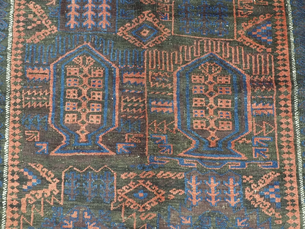 A rectangular antique hand-knotted wool carpet featuring deep indigo blue and madder red geometric motifs with geometric borders and white star details. View X