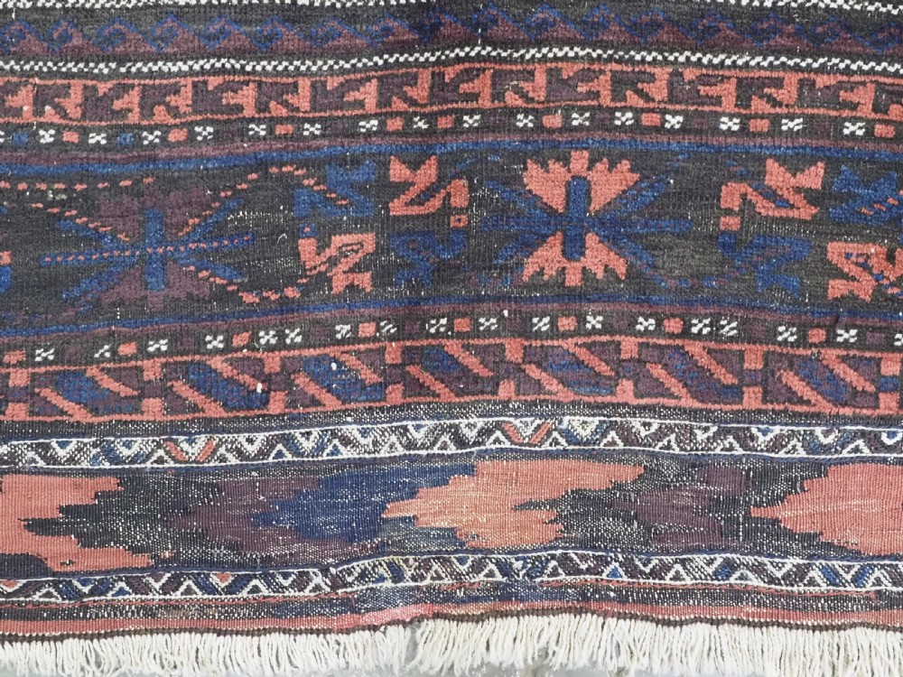 A rectangular antique hand-knotted wool carpet featuring deep indigo blue and madder red geometric motifs with geometric borders and white star details. View XII