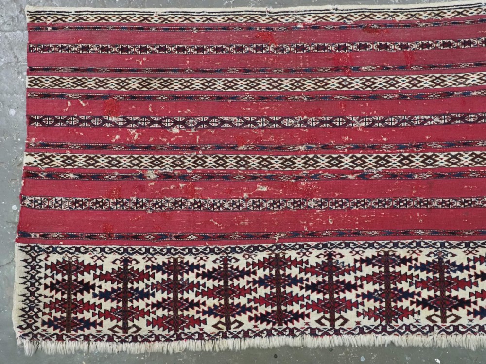 An antique Tekke Turkmen Ak chuval face displaying red and dark blue horizontal bands above a patterned ivory geometric lower panel. View II