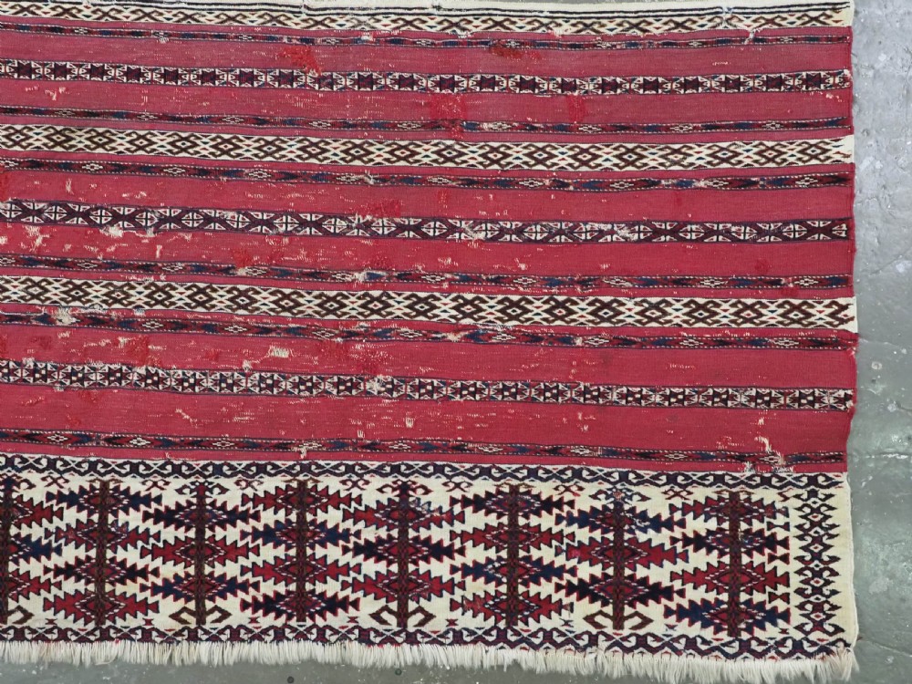 An antique Tekke Turkmen Ak chuval face displaying red and dark blue horizontal bands above a patterned ivory geometric lower panel. View III