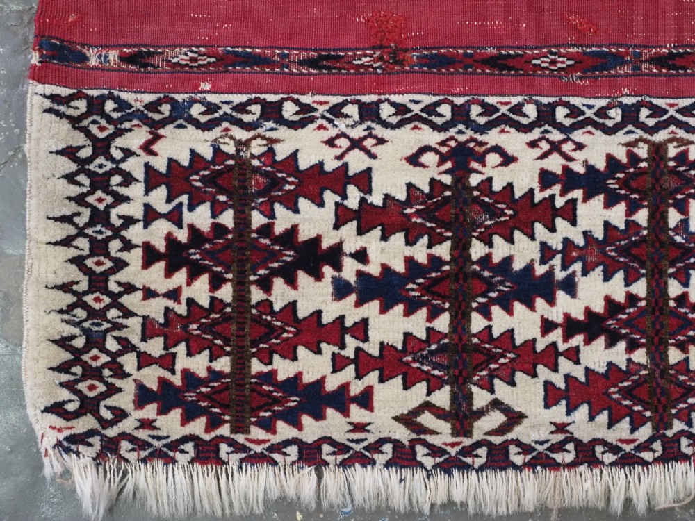 An antique Tekke Turkmen Ak chuval face displaying red and dark blue horizontal bands above a patterned ivory geometric lower panel. View IV