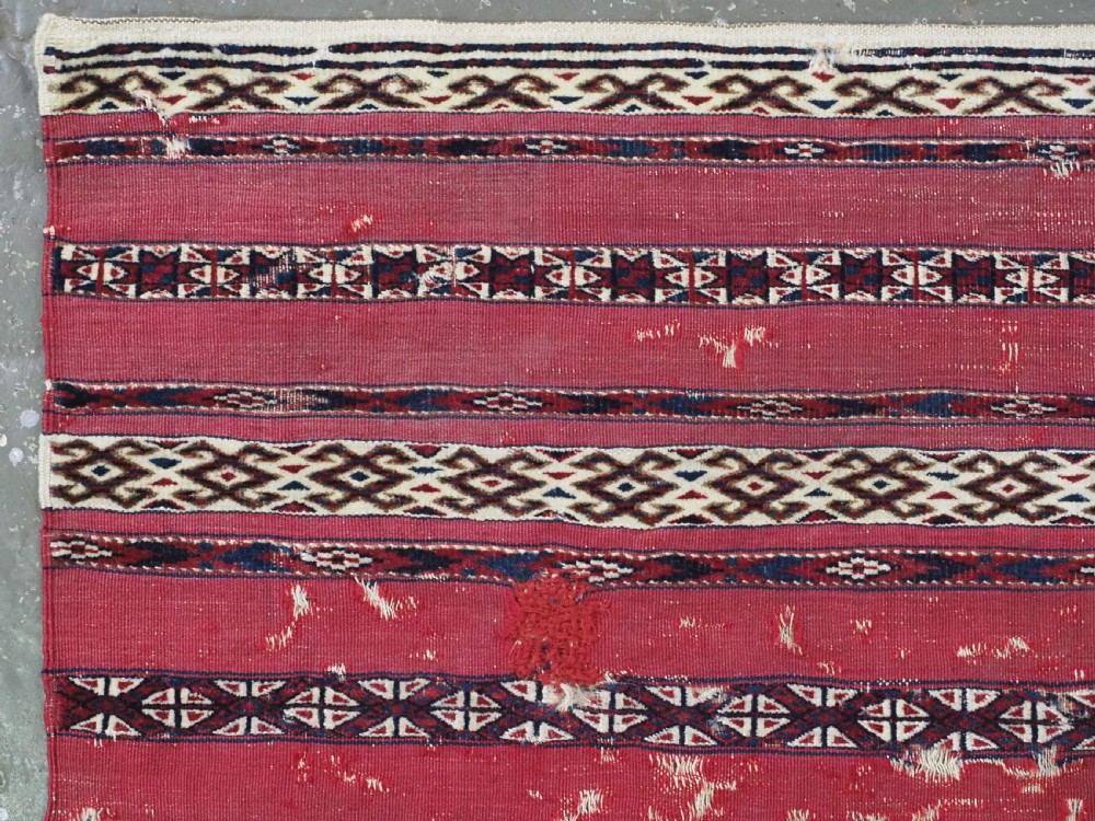 An antique Tekke Turkmen Ak chuval face displaying red and dark blue horizontal bands above a patterned ivory geometric lower panel. View V