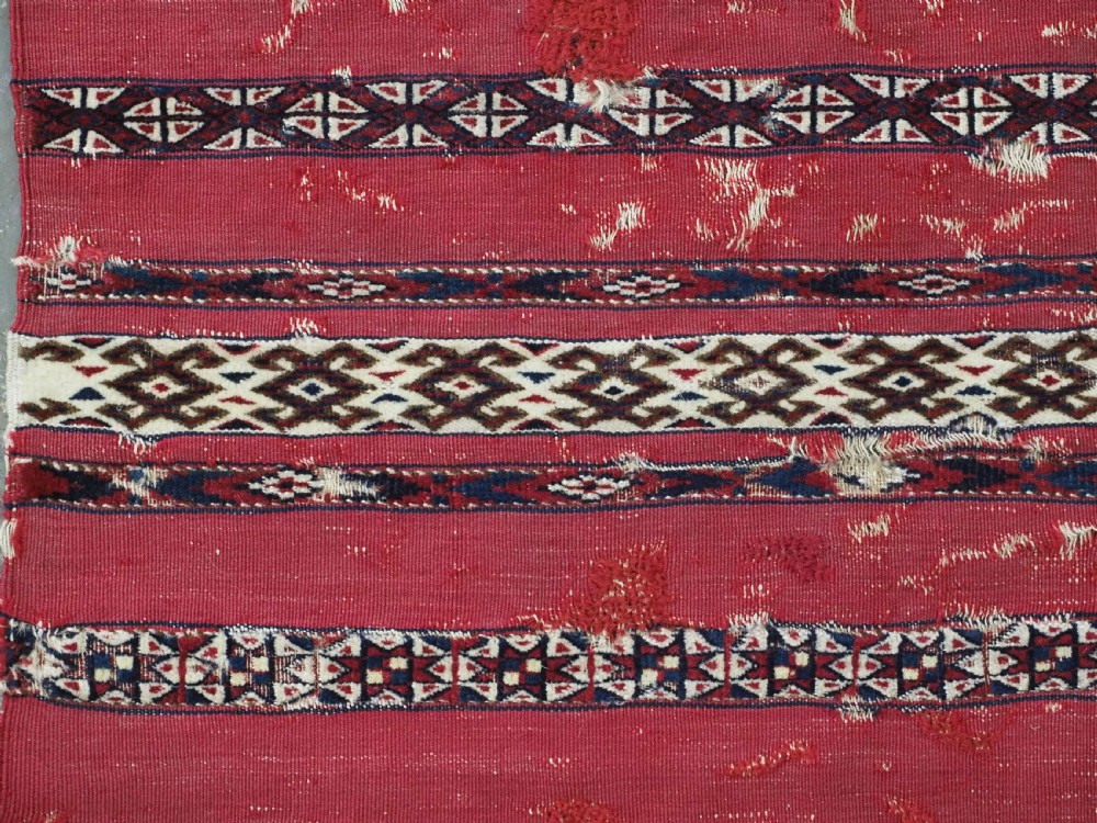 An antique Tekke Turkmen Ak chuval face displaying red and dark blue horizontal bands above a patterned ivory geometric lower panel. View VI