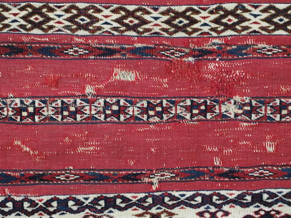 An antique Tekke Turkmen Ak chuval face displaying red and dark blue horizontal bands above a patterned ivory geometric lower panel. View IX