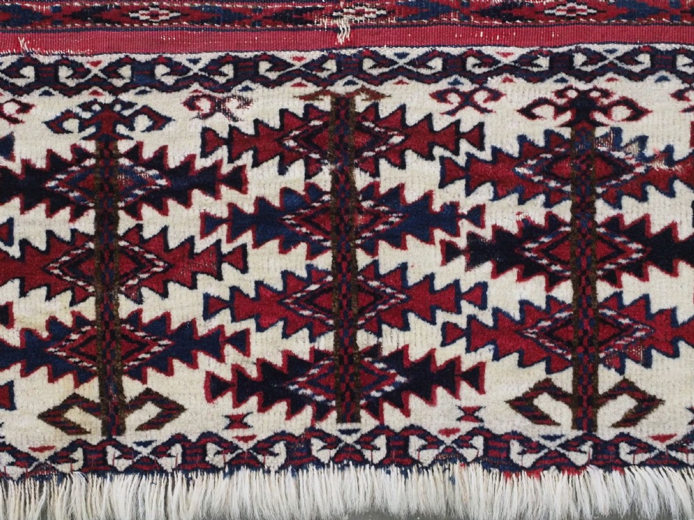 An antique Tekke Turkmen Ak chuval face displaying red and dark blue horizontal bands above a patterned ivory geometric lower panel. View X