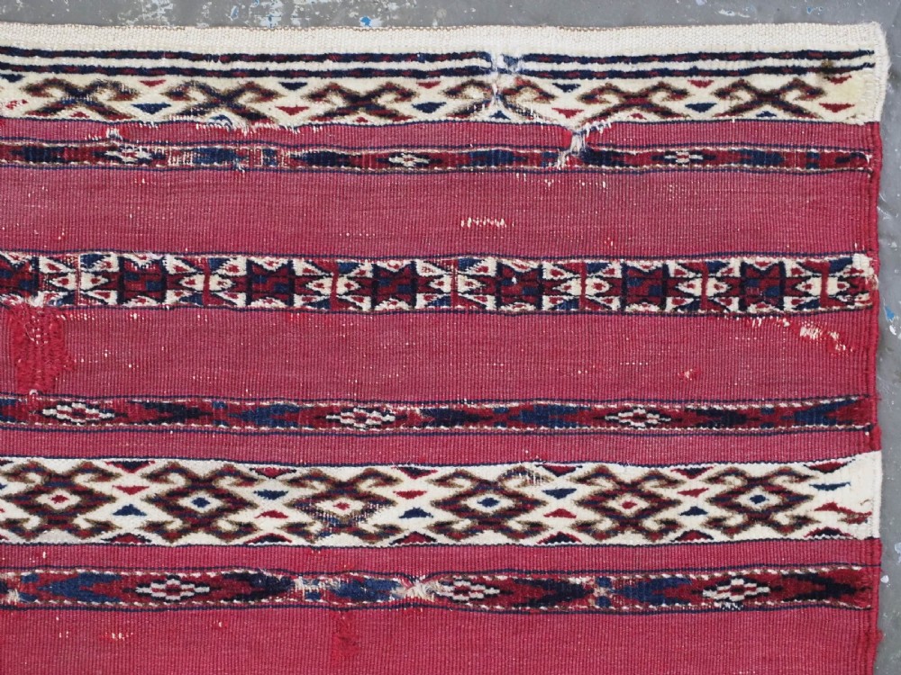An antique Tekke Turkmen Ak chuval face displaying red and dark blue horizontal bands above a patterned ivory geometric lower panel. View XI
