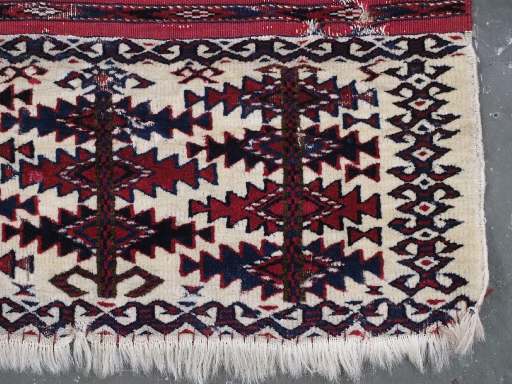 An antique Tekke Turkmen Ak chuval face displaying red and dark blue horizontal bands above a patterned ivory geometric lower panel. View XII