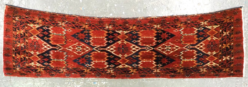 A horizontal antique hand-knotted Turkmen wool torba featuring rust red, black, and cream geometric ikat motifs.