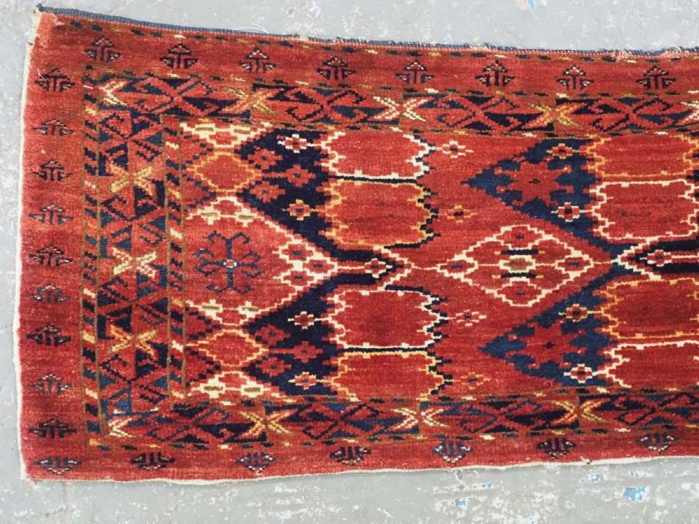 A horizontal antique hand-knotted Turkmen wool torba featuring rust red, black, and cream geometric ikat motifs. View II