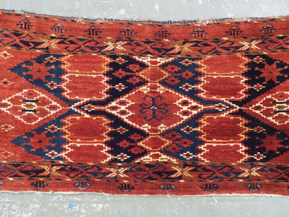 A horizontal antique hand-knotted Turkmen wool torba featuring rust red, black, and cream geometric ikat motifs. View III