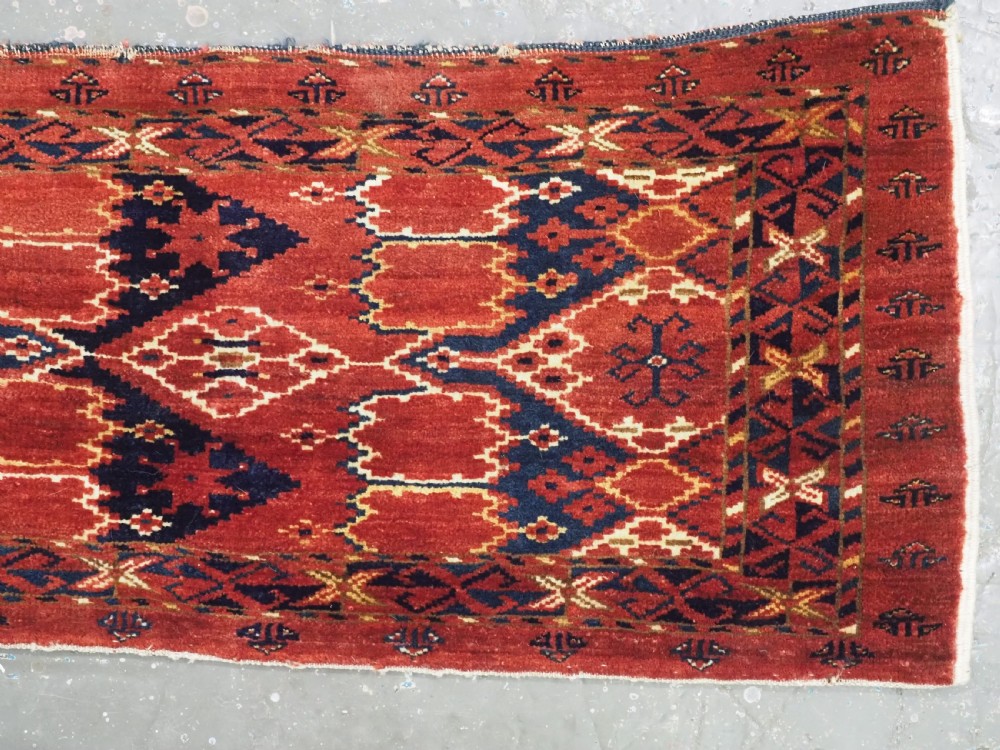 A horizontal antique hand-knotted Turkmen wool torba featuring rust red, black, and cream geometric ikat motifs. View IV