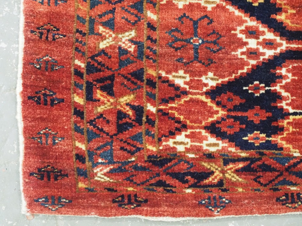 A horizontal antique hand-knotted Turkmen wool torba featuring rust red, black, and cream geometric ikat motifs. View V