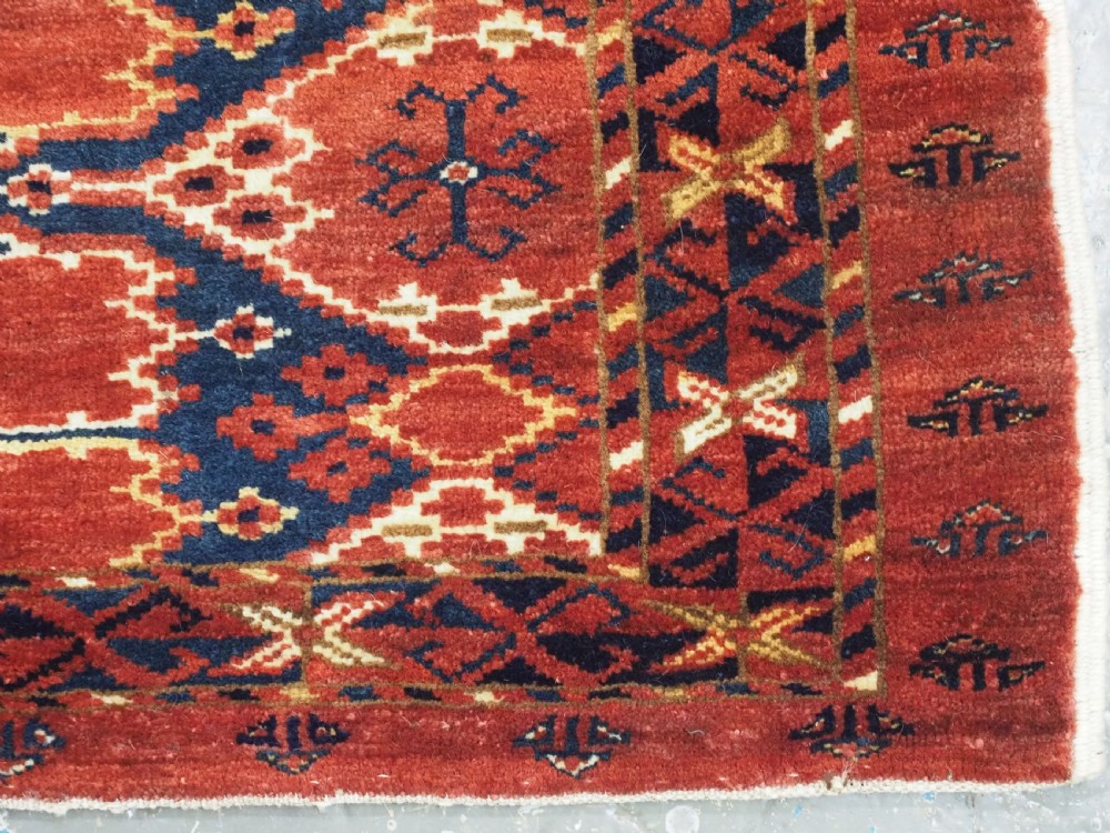 A horizontal antique hand-knotted Turkmen wool torba featuring rust red, black, and cream geometric ikat motifs. View X