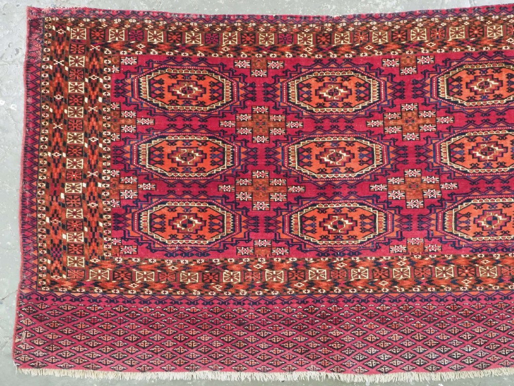 An antique woven wool Turkmen chuval face featuring nine primary octagonal gul motifs on a deep red field framed by geometric borders. View II