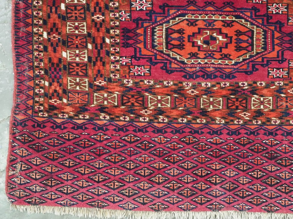 An antique woven wool Turkmen chuval face featuring nine primary octagonal gul motifs on a deep red field framed by geometric borders. View V