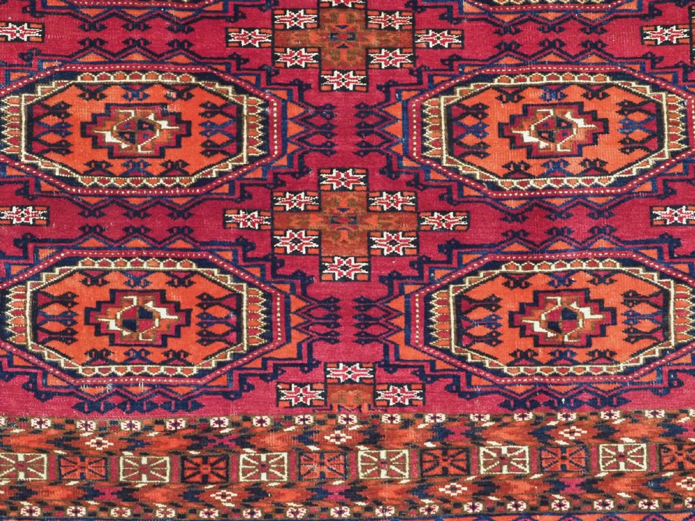 An antique woven wool Turkmen chuval face featuring nine primary octagonal gul motifs on a deep red field framed by geometric borders. View VI