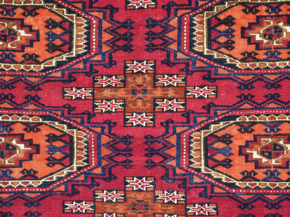 An antique woven wool Turkmen chuval face featuring nine primary octagonal gul motifs on a deep red field framed by geometric borders. View VII