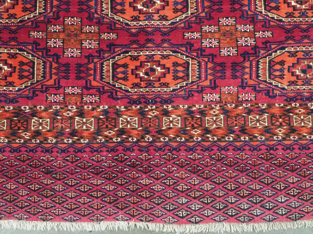 An antique woven wool Turkmen chuval face featuring nine primary octagonal gul motifs on a deep red field framed by geometric borders. View VIII
