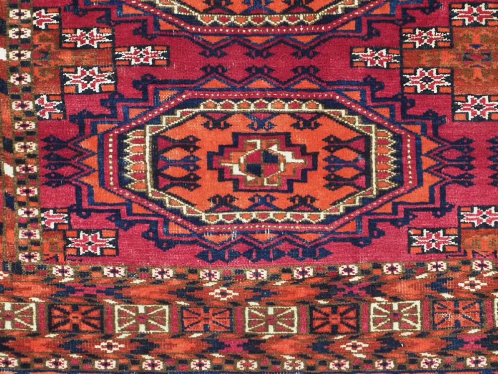An antique woven wool Turkmen chuval face featuring nine primary octagonal gul motifs on a deep red field framed by geometric borders. View IX