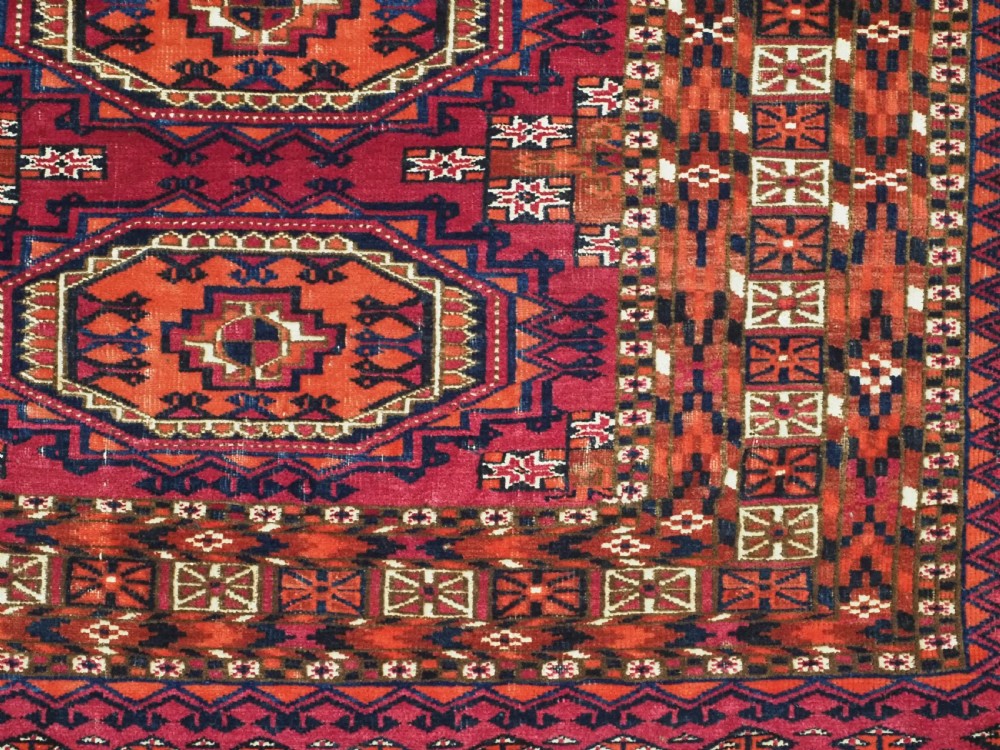 An antique woven wool Turkmen chuval face featuring nine primary octagonal gul motifs on a deep red field framed by geometric borders. View X