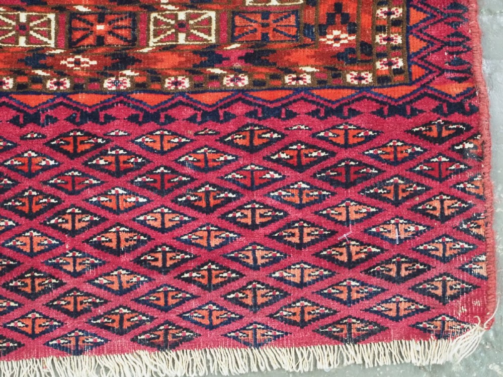 An antique woven wool Turkmen chuval face featuring nine primary octagonal gul motifs on a deep red field framed by geometric borders. View XII