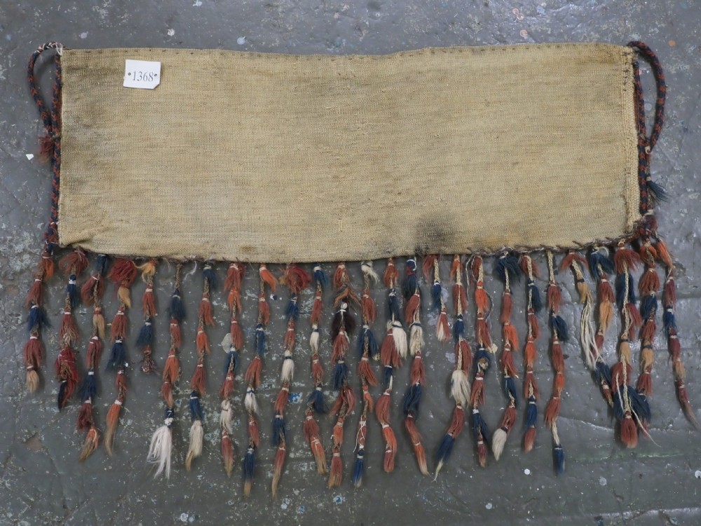 An antique rectangular Yomut Turkmen wool textile featuring intricate geometric lattice patterns in terracotta red, navy blue, and ivory, finished with a fringe of multi-coloured tassels along the bottom edge. View VII