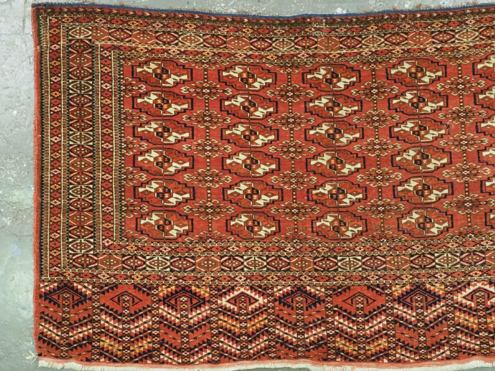 An antique Tekke Turkmen chuval bag face featuring repeating geometric gul motifs on a rust red wool pile with a detailed elem skirt border. View II