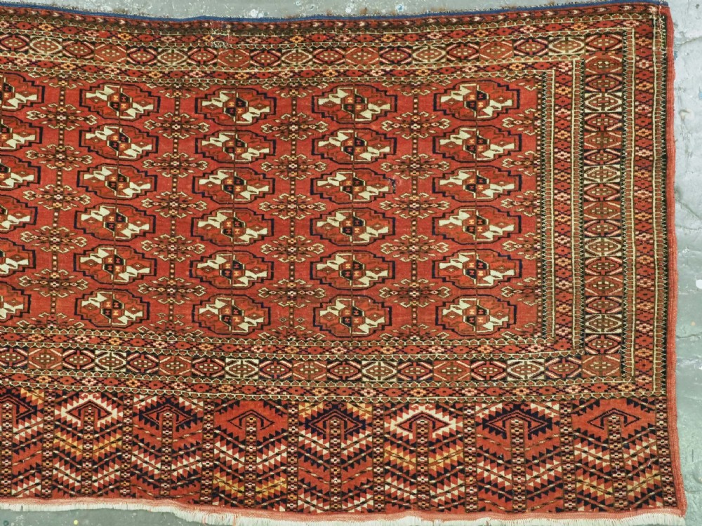 An antique Tekke Turkmen chuval bag face featuring repeating geometric gul motifs on a rust red wool pile with a detailed elem skirt border. View III