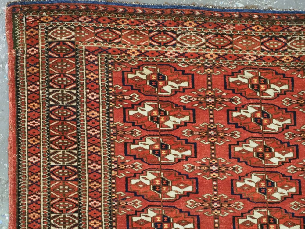 An antique Tekke Turkmen chuval bag face featuring repeating geometric gul motifs on a rust red wool pile with a detailed elem skirt border. View IV