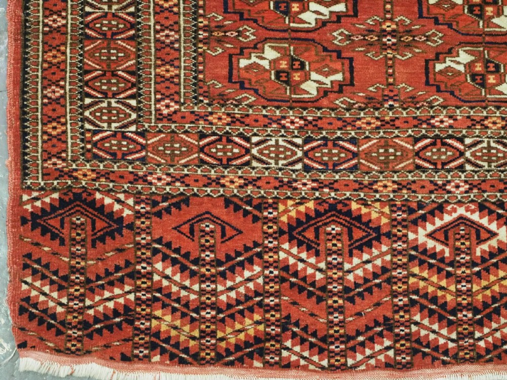An antique Tekke Turkmen chuval bag face featuring repeating geometric gul motifs on a rust red wool pile with a detailed elem skirt border. View V