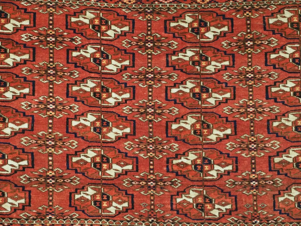 An antique Tekke Turkmen chuval bag face featuring repeating geometric gul motifs on a rust red wool pile with a detailed elem skirt border. View VI