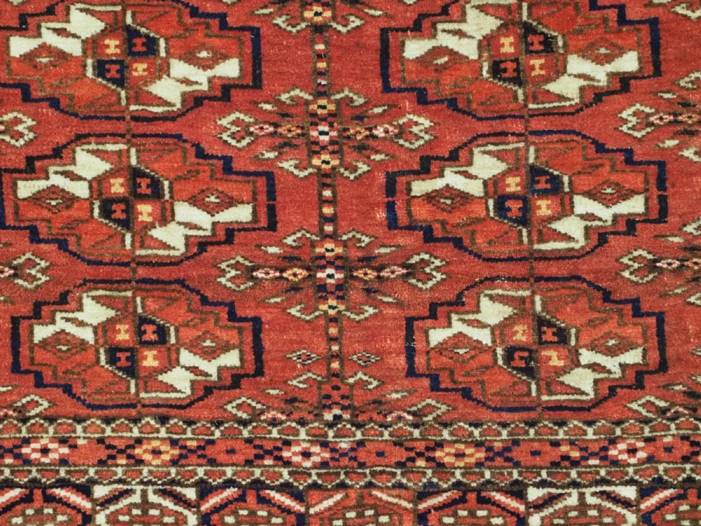 An antique Tekke Turkmen chuval bag face featuring repeating geometric gul motifs on a rust red wool pile with a detailed elem skirt border. View VII