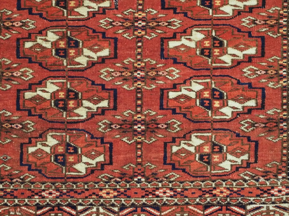 An antique Tekke Turkmen chuval bag face featuring repeating geometric gul motifs on a rust red wool pile with a detailed elem skirt border. View VIII